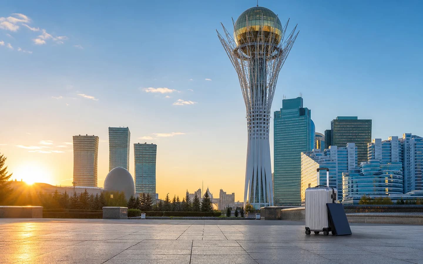 Medical travel documents and luggage beside Bayterek Tower in Astana, Kazakhstan